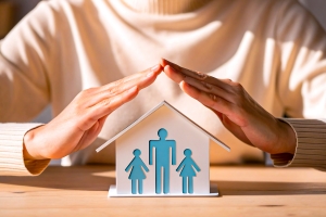 Hands Protecting Paper House with Family Symbol Representing Homeowners Insurance